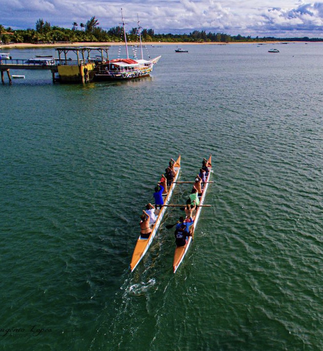 Vista aérea de duas canoas remando próximas a um barco ancorado