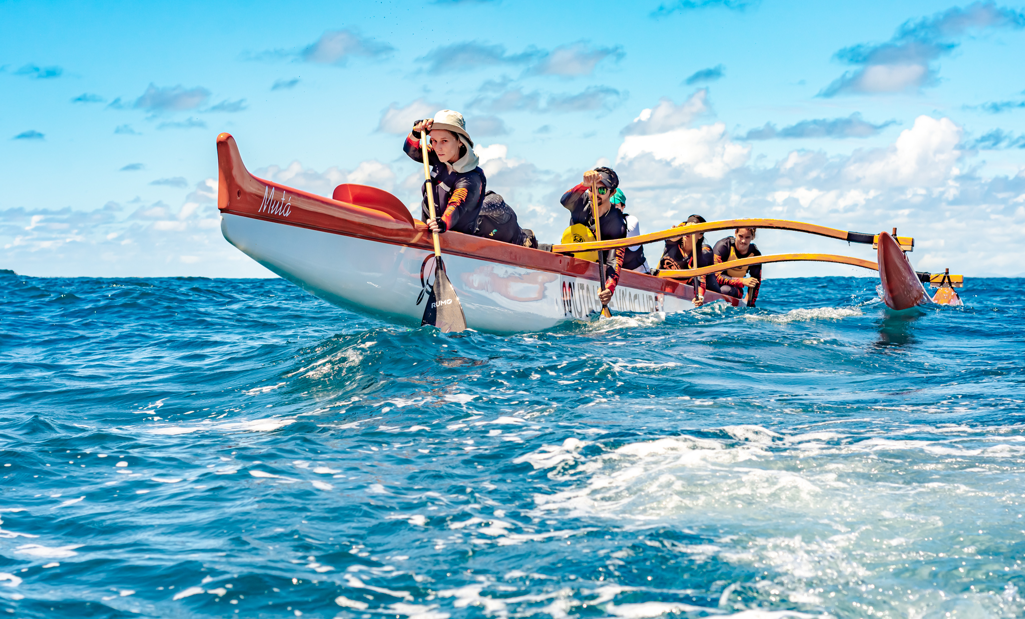 Remadora de chapéu na proa da canoa em alto mar