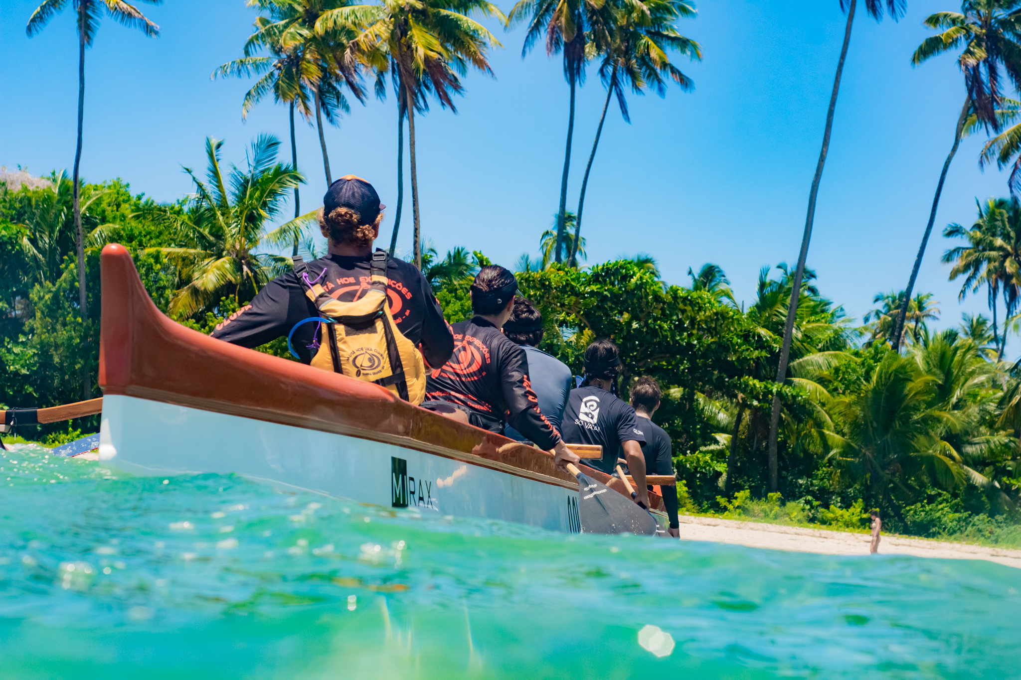 Tripulação saindo com a canoa em praia de coqueiros